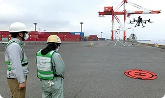港湾ヤードで作業員がドローン点検を準備している様子