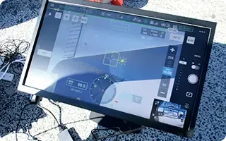自動飛行中のドローン操作タブレットを確認している現場